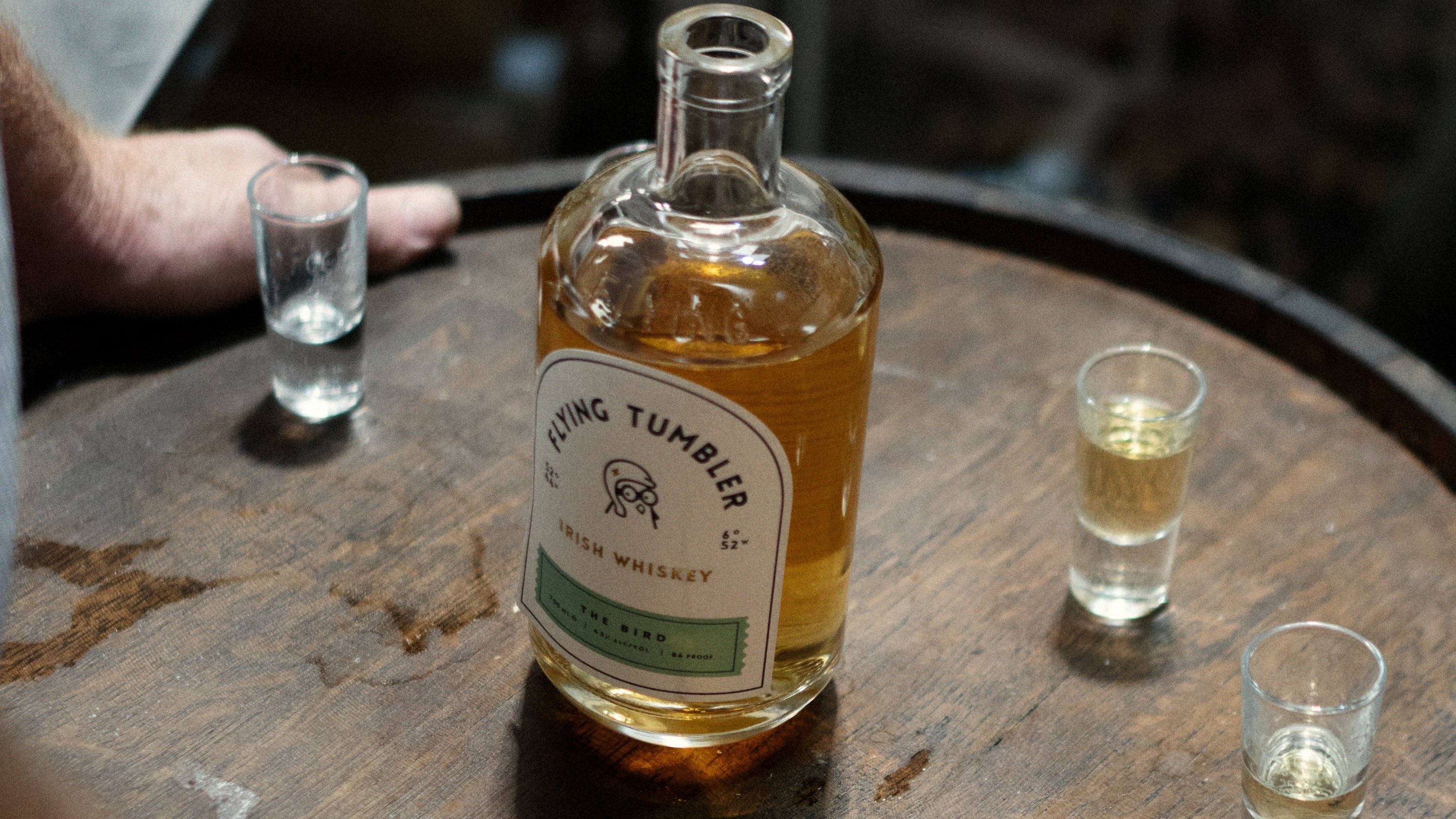 Bottle of Flying Tumbler Irish whiskey on a barrel with tasting glasses